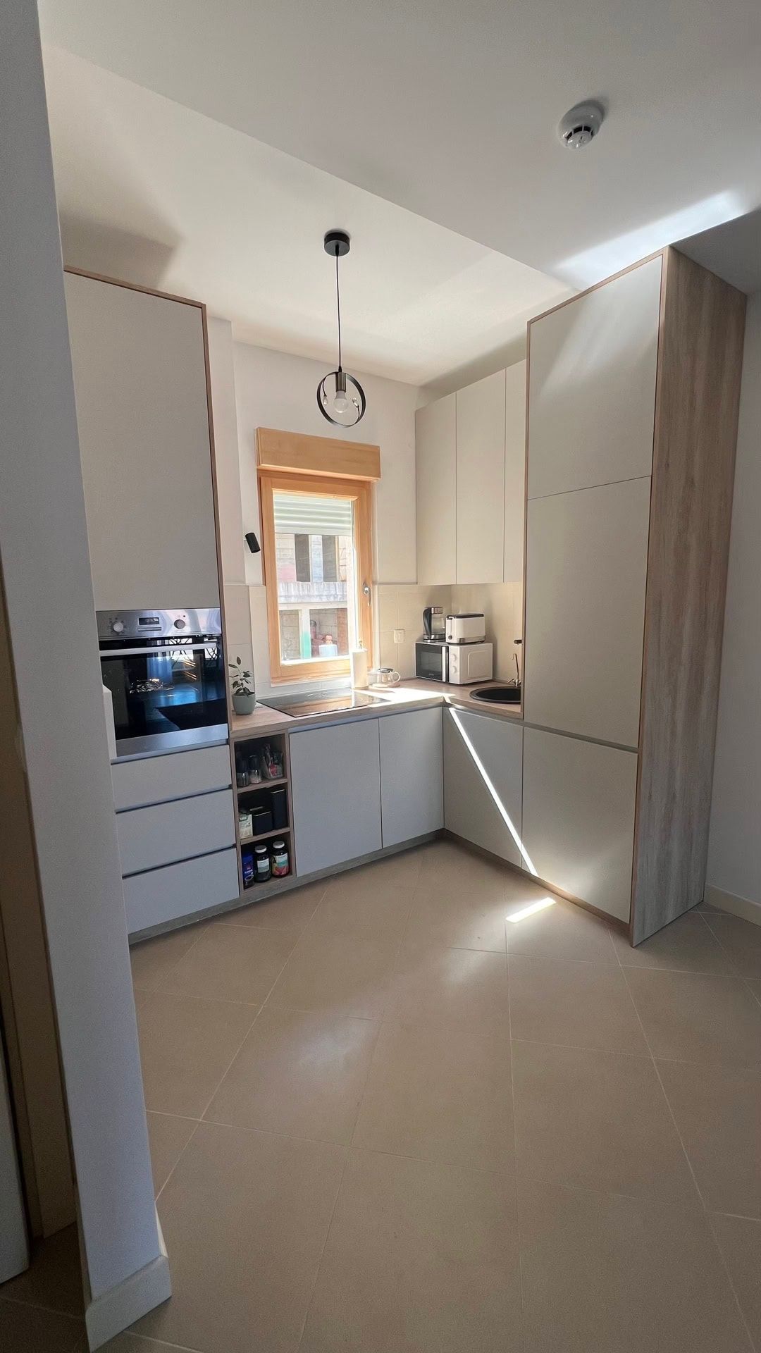 Modern kitchen in an apartment in Dobrota, Montenegro: light-colored kitchen set, built-in appliances, and tiled flooring.