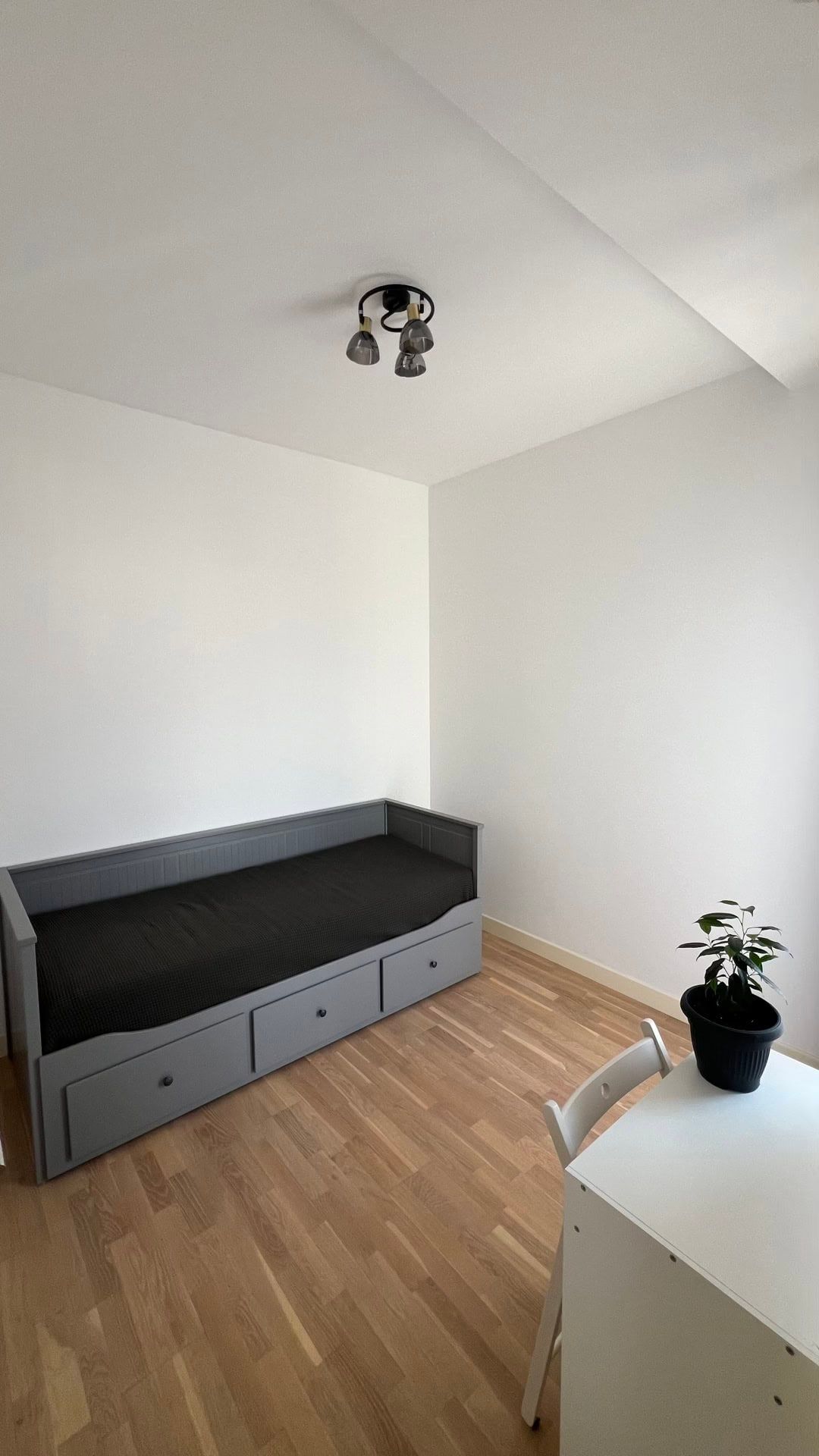 Bright bedroom in an apartment, Dobrota, Montenegro: grey bed with drawers, parquet flooring, and a white desk.