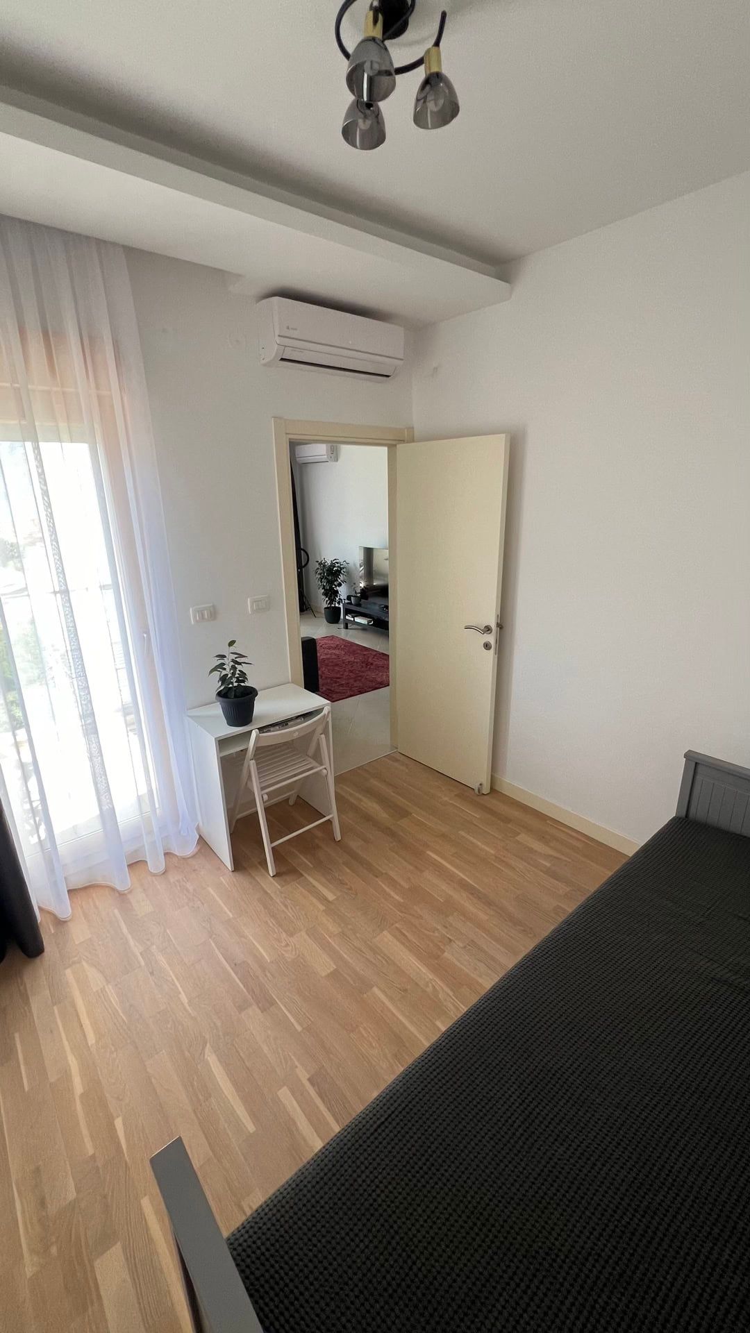 Bright bedroom with a bed, desk, and balcony access in an apartment, Dobrota, Montenegro.
