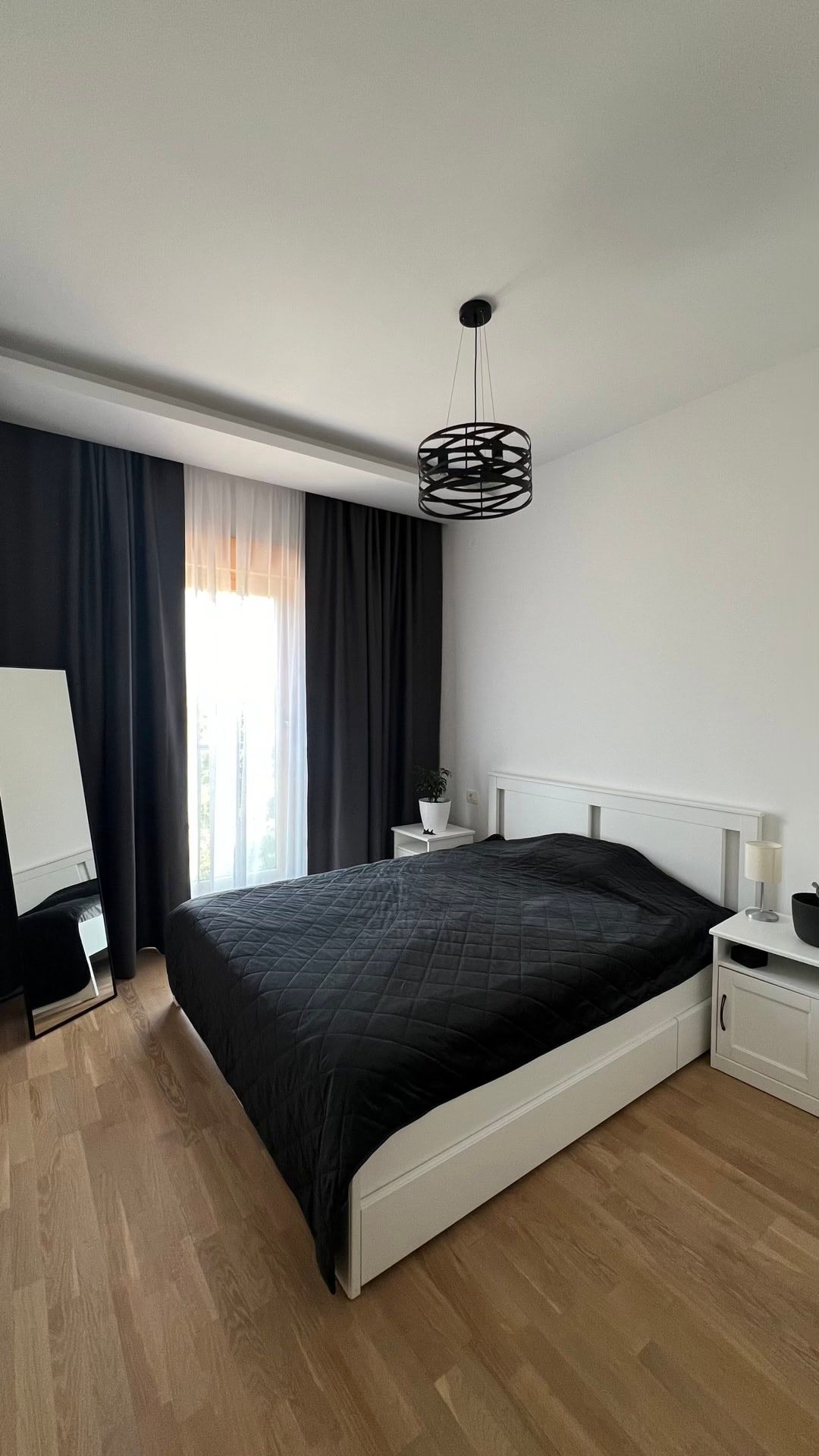 Modern bedroom in an apartment in Dobrota, Montenegro: white furniture, a double bed, and stylish dark curtains.