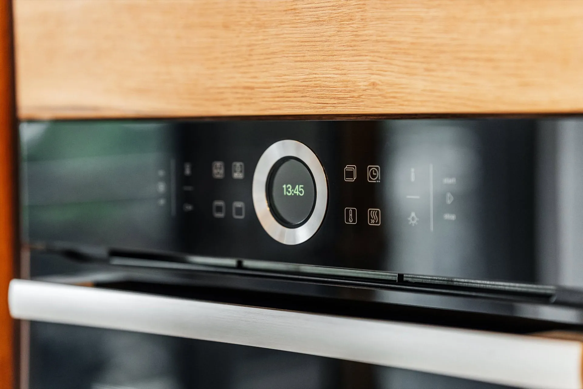 Close-up of a built-in oven control panel with a digital clock display and wooden countertop above.
