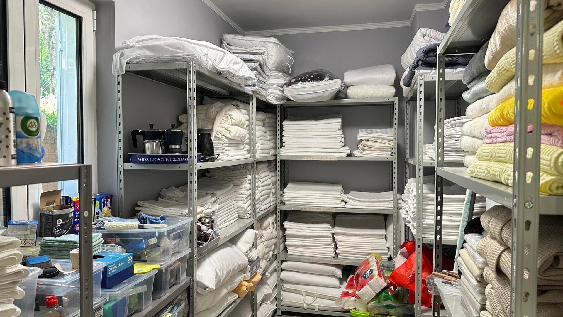 Utility room with metal shelving and a stock of bed linen in a hotel, Pržno, Montenegro.