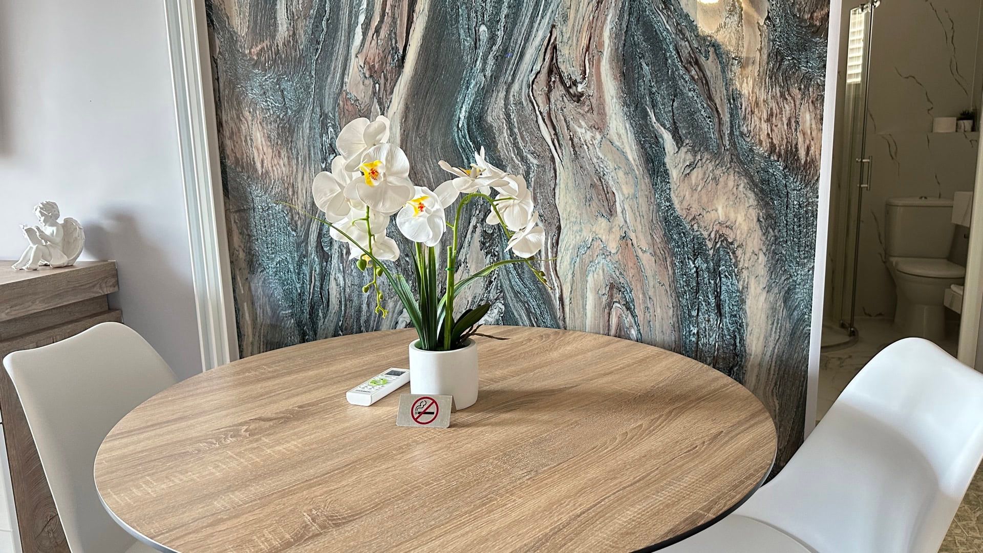 Dining area in a hotel in Pržno, Montenegro: round table, white chairs, and an accent wall with a marble pattern.