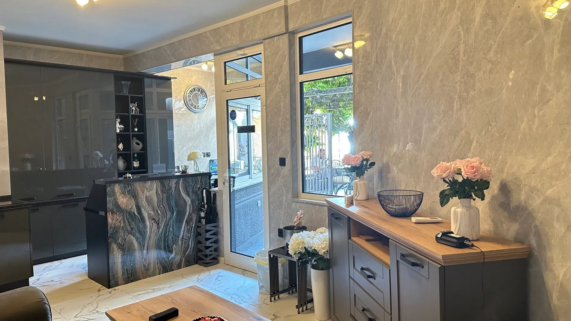 Interior featuring a marble bar counter, dark glossy cabinets, and a wooden sideboard with flowers and a card terminal.