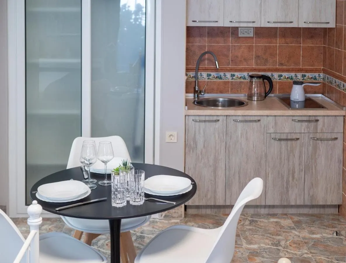 Kitchen area with wooden cabinets, sink, stove, and a black dining table set with plates and glasses.