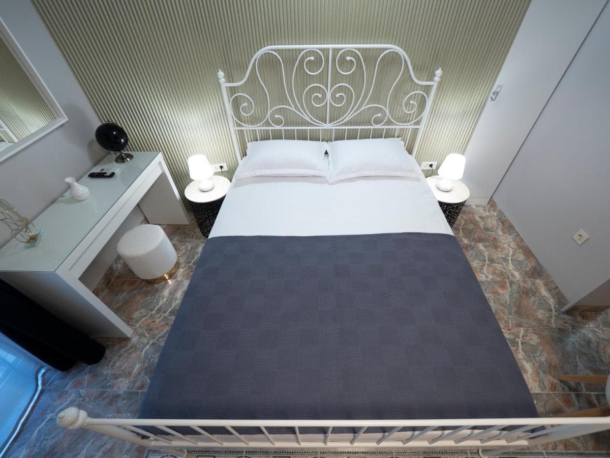 Bedroom with a wrought-iron bed and vanity table in a hotel in Pržno, Montenegro. Modern interior with marble flooring.