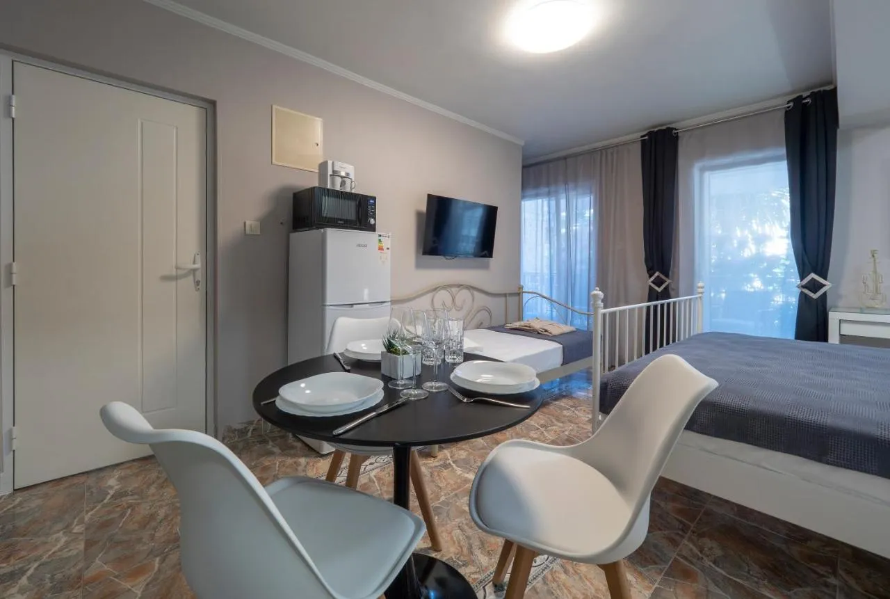 Room containing a bed, dining table, fridge, and TV, combining sleeping and kitchen areas in one space.