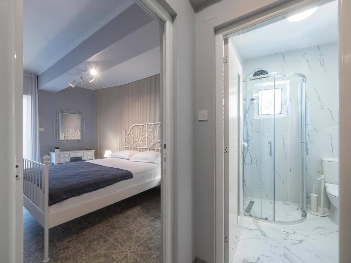 Bedroom and bathroom with a shower cabin in a hotel in Pržno, Montenegro: modern interior and light finishes.