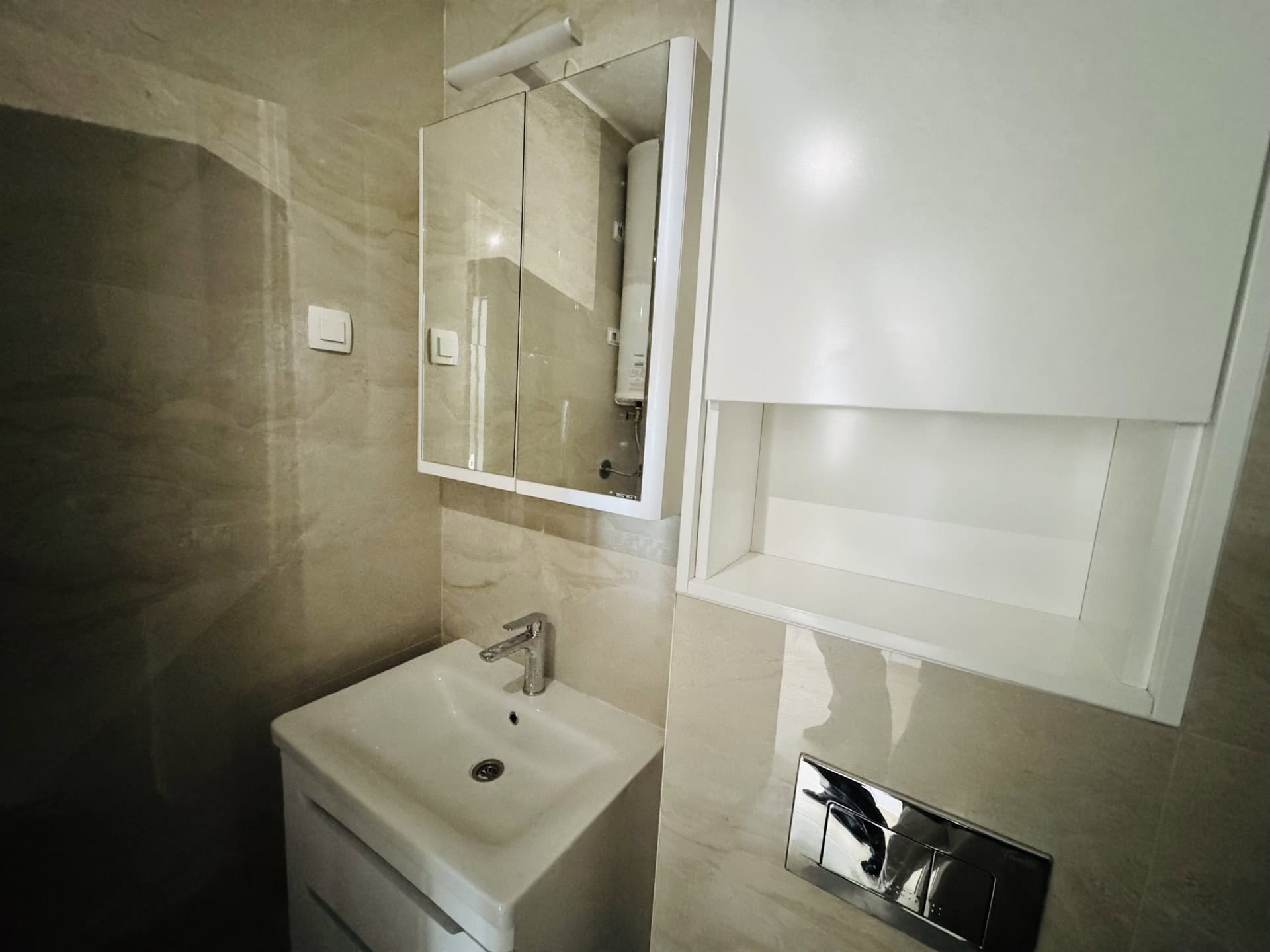 Modern bathroom with white furniture and beige tiles in an apartment, Becici, Montenegro.