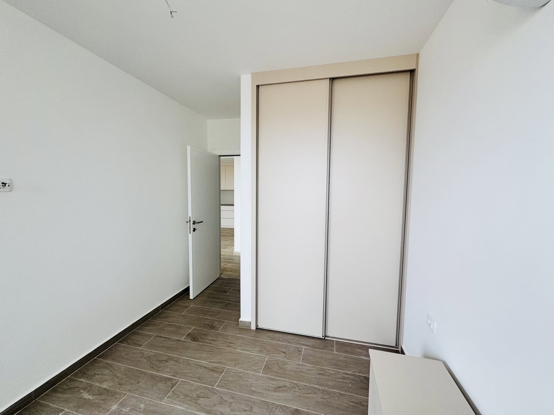 Bright bedroom with a built-in sliding wardrobe and wood-style finishes in a new apartment, Becici, Montenegro.