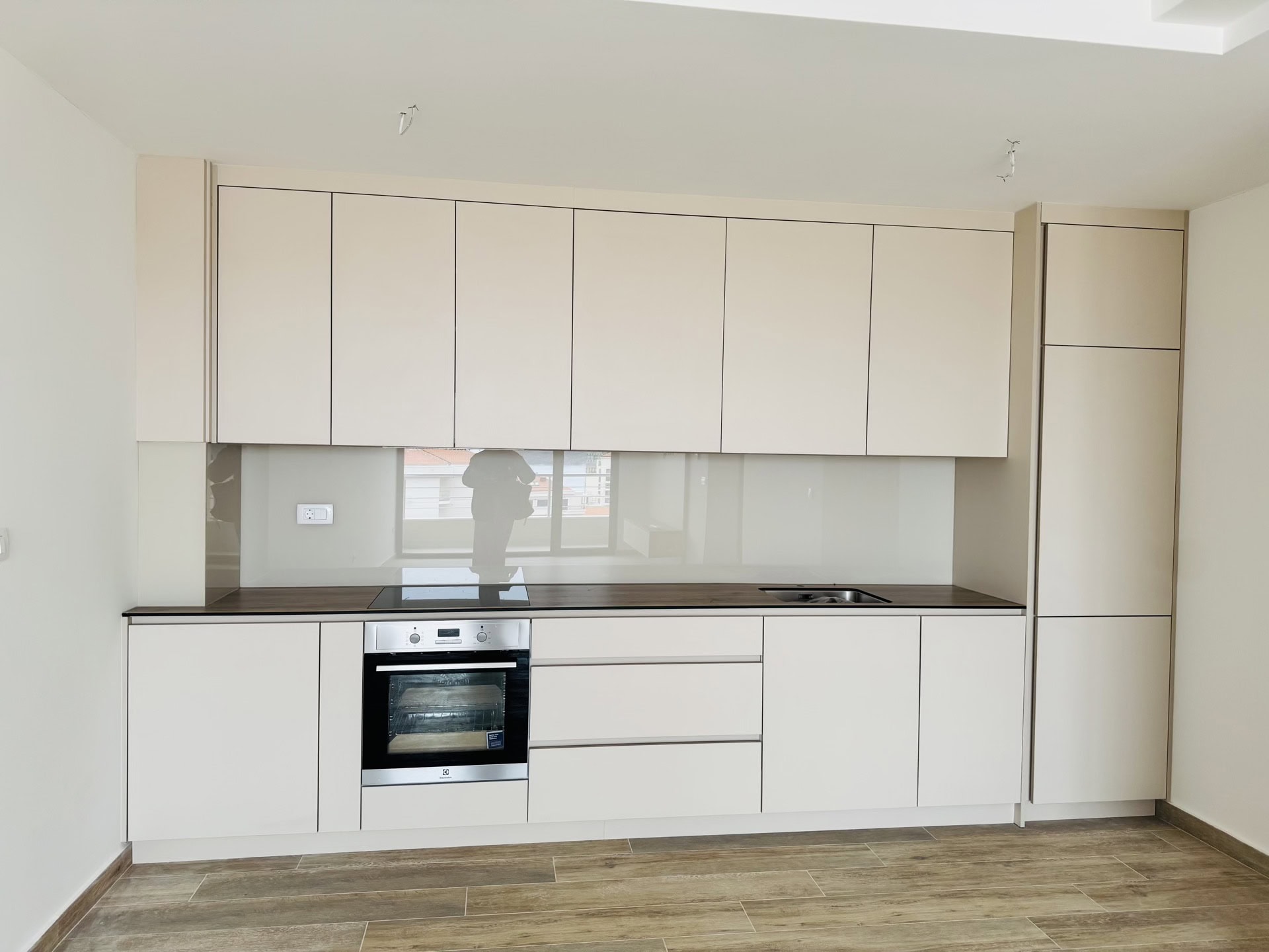 Modern bright kitchen in an apartment in Bečići, Montenegro: built-in appliances, matte fronts, and a dark countertop.