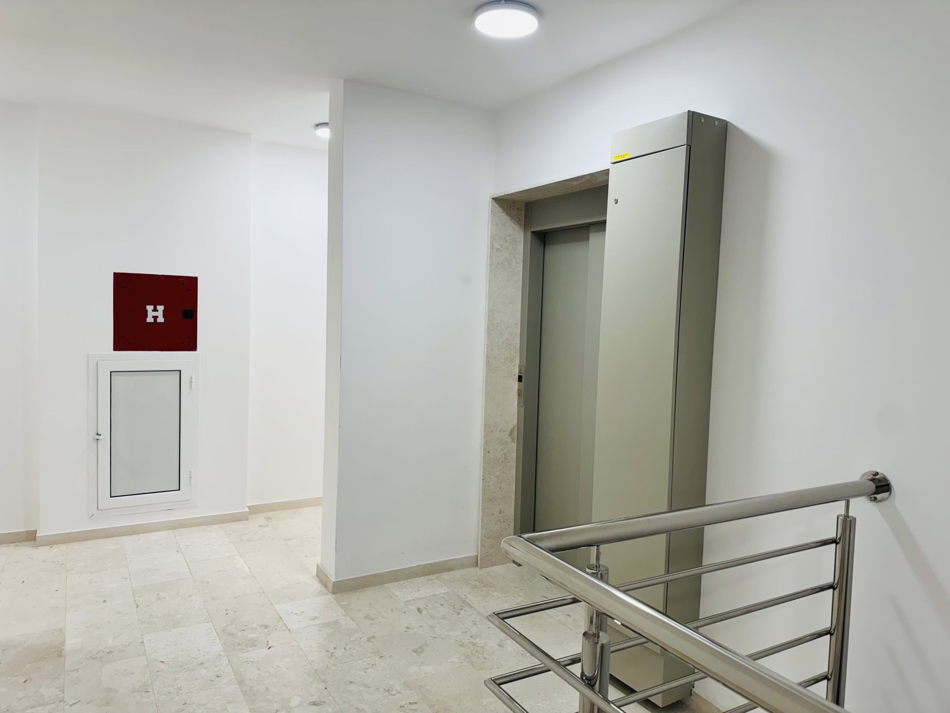 Modern elevator lobby in a residential complex in Bečići, Montenegro: light finishes, tile, and metal railings.
