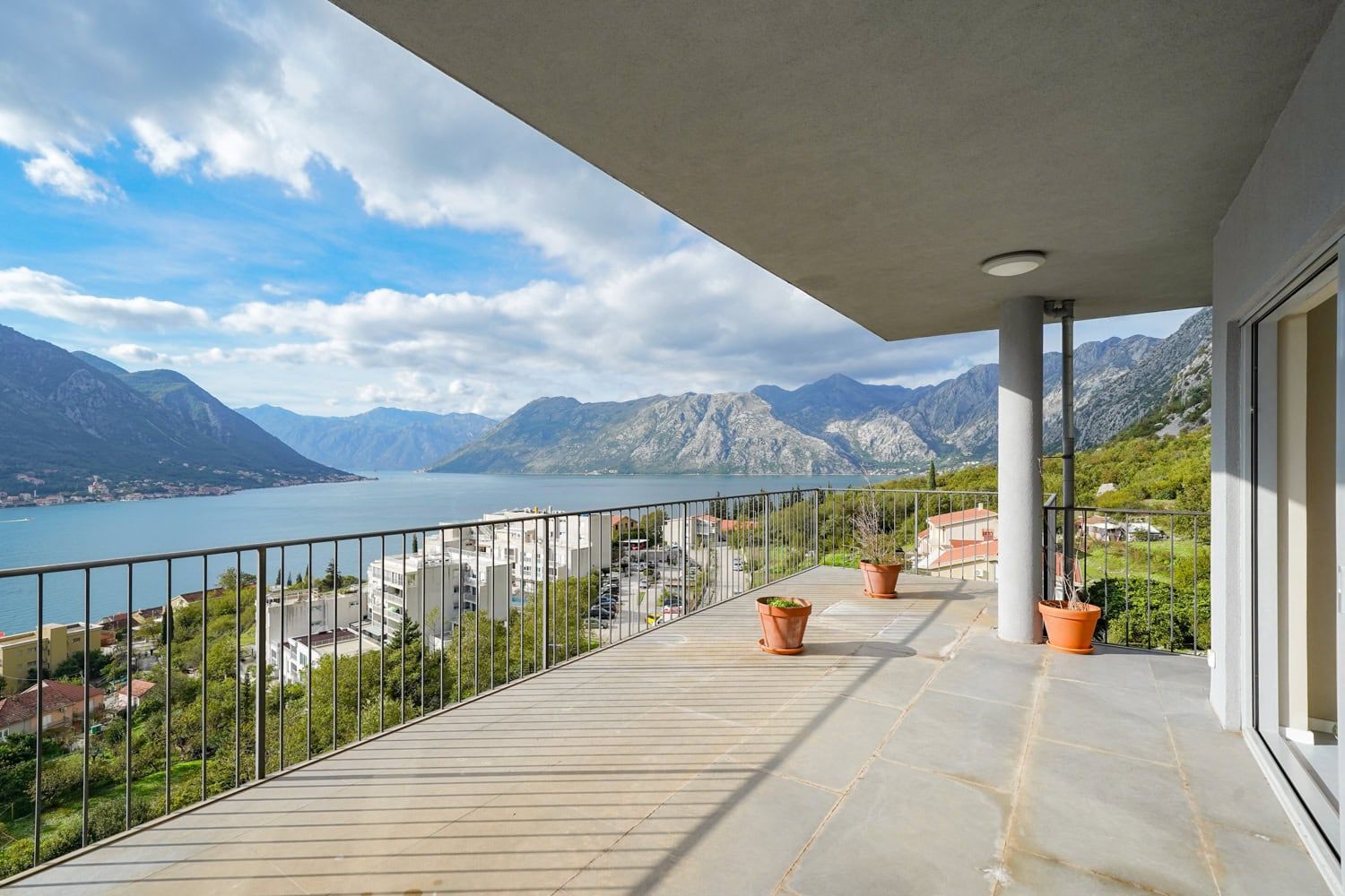 Spacious balcony with panoramic views of Kotor Bay and the mountains, apartment in Dobrota, Montenegro, stone floor.