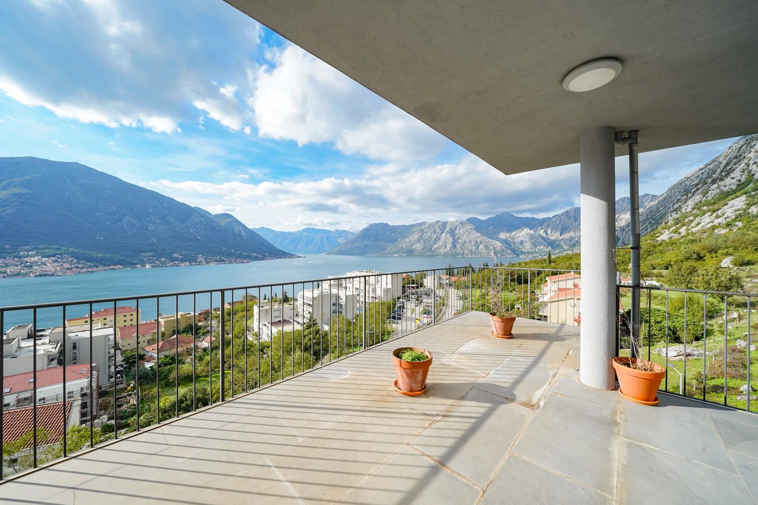 Spacious balcony with panoramic views of Kotor Bay and the mountains in Dobrota, Montenegro. Stone floor finish.