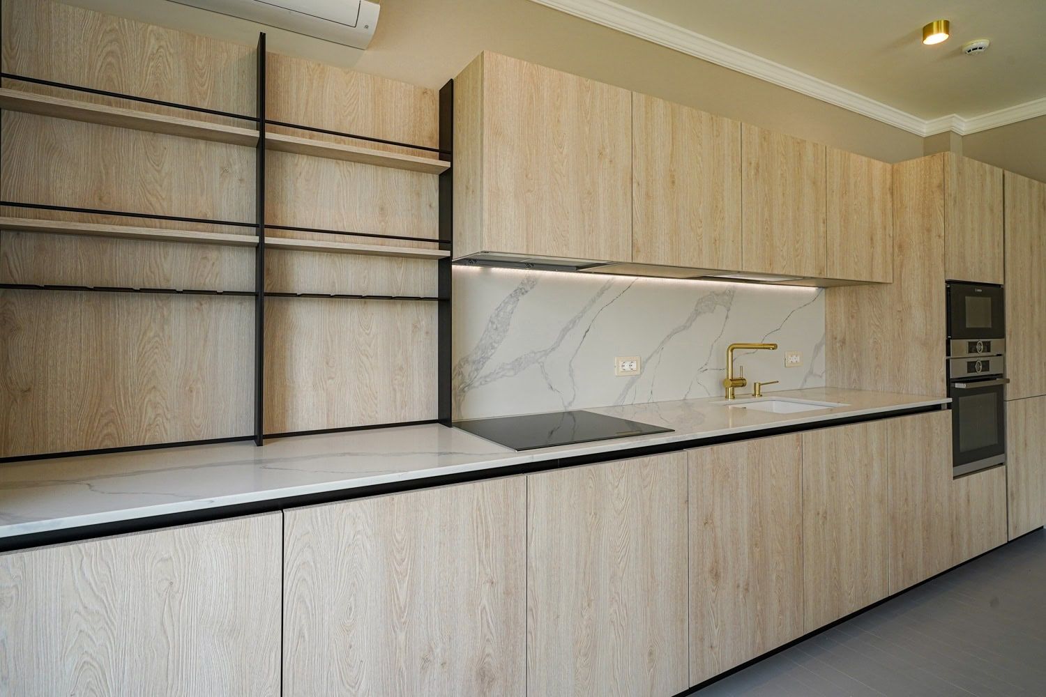Modern kitchen in an apartment in Dobrota, Montenegro: wood-look fronts, marble backsplash, and built-in appliances.