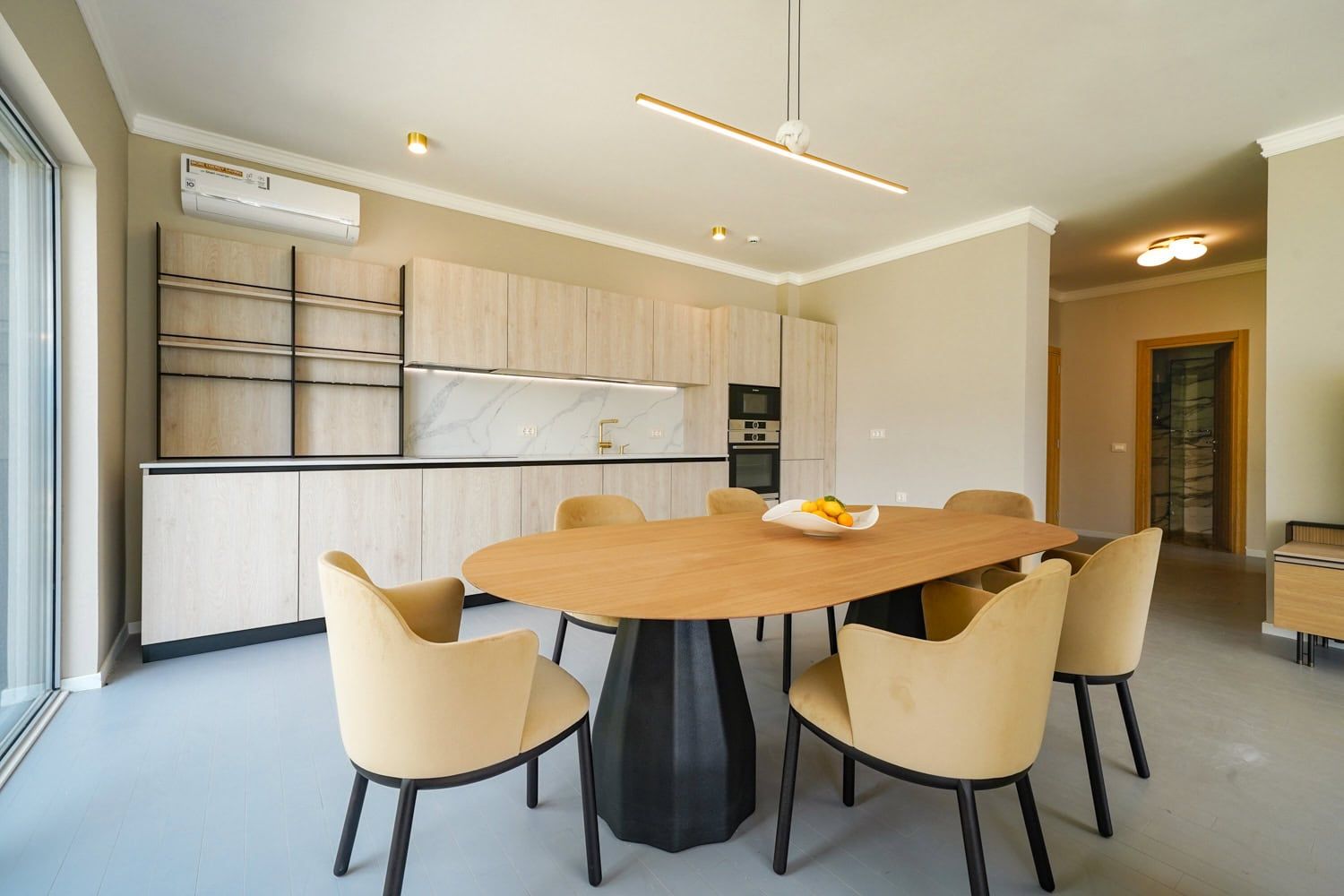 Modern kitchen-dining room in an apartment in Dobrota, Montenegro: light-colored furniture, an oval table, and a stylish interior.