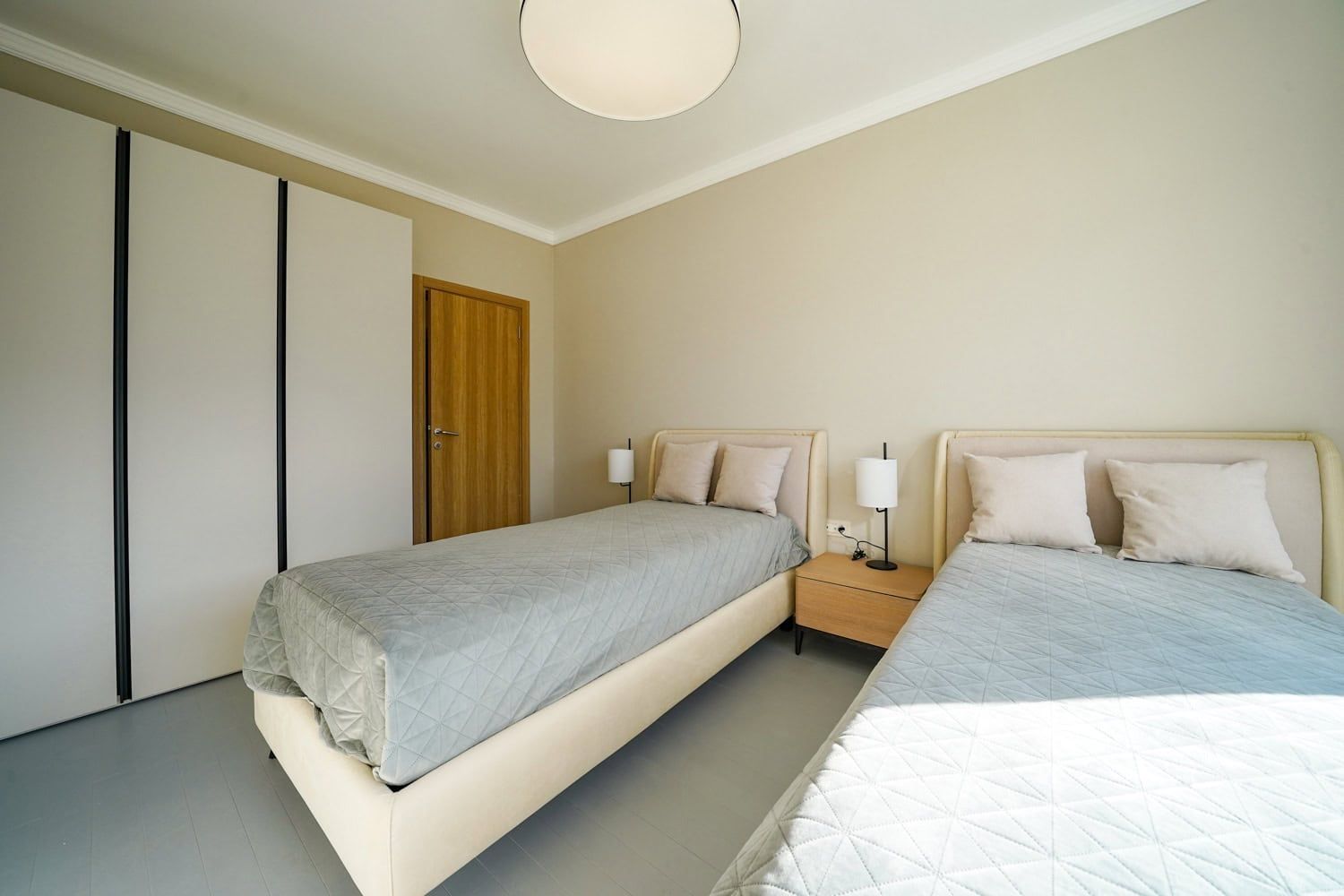 Bright bedroom with two beds and a built-in wardrobe in an apartment, Dobrota, Montenegro.