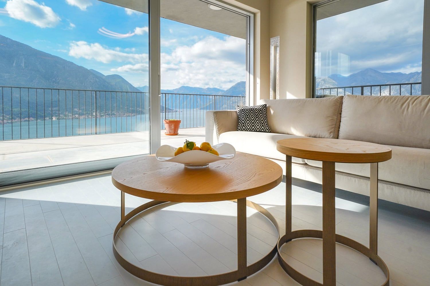 Living room in an apartment in Dobrota, Montenegro: panoramic view of the Bay of Kotor, light-colored furniture, and a terrace.