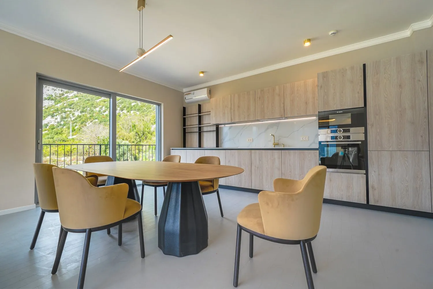 Modern kitchen with wooden cabinets, a dining table, and mustard chairs near a large window.
