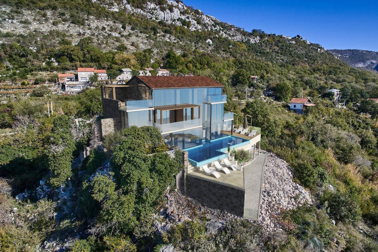Modern villa with panoramic windows, a terrace, and a pool in the mountains of Petrovac, Montenegro. Aerial view.