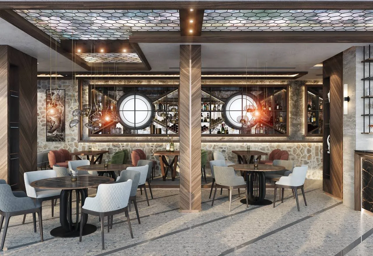 Restaurant or bar interior featuring round tables, upholstered chairs, stone walls, and a backlit wine display.