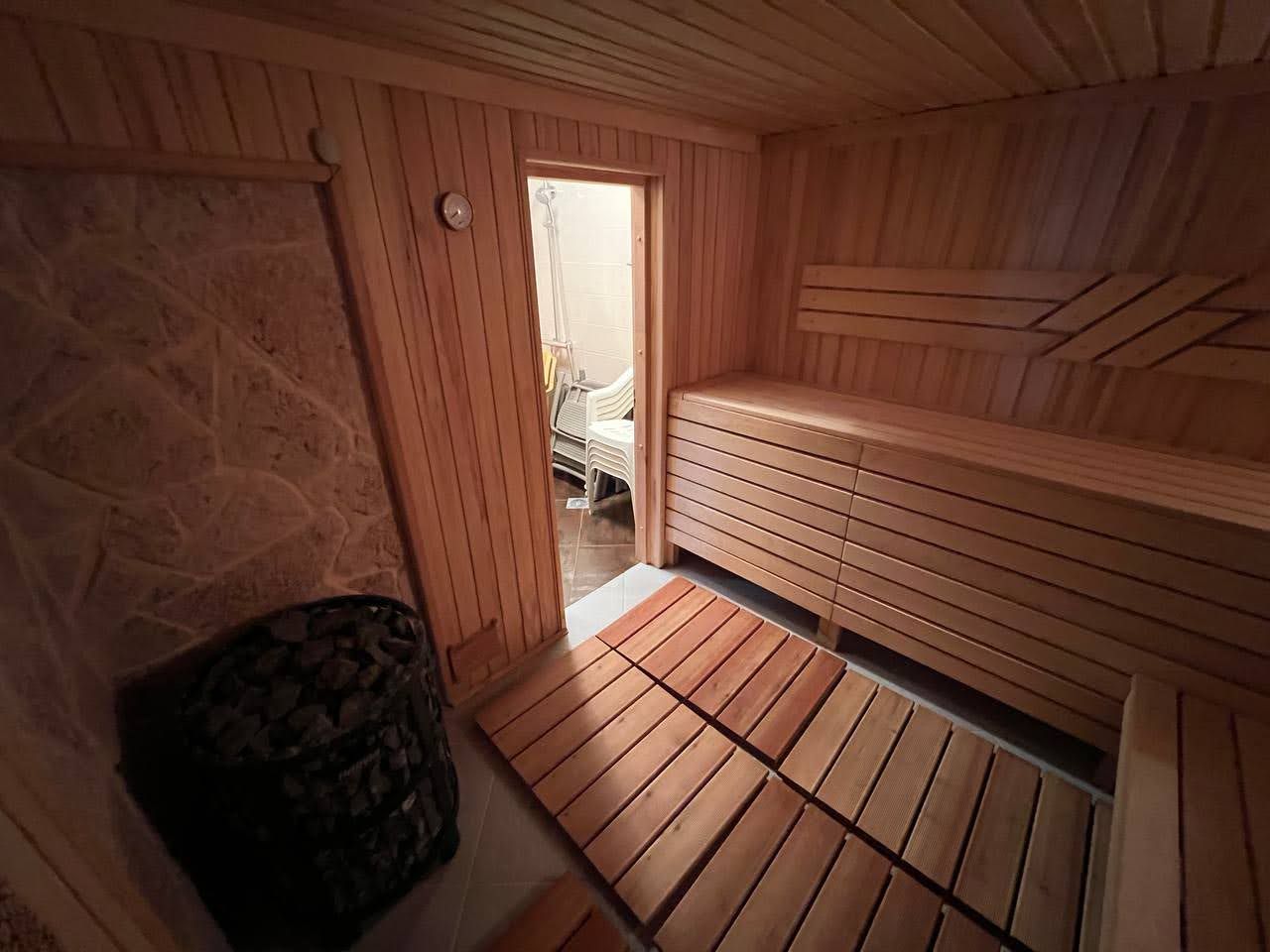 Wooden sauna with stone finishes in a villa in Kamenari, Montenegro: steam room interior with benches and a sauna stove.
