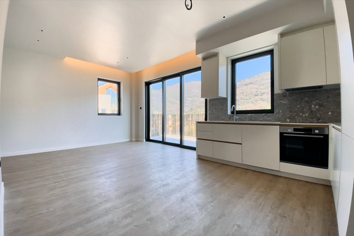 Modern kitchen-living room in an apartment in Tivat, Montenegro: bright interior, built-in appliances, and mountain views.
