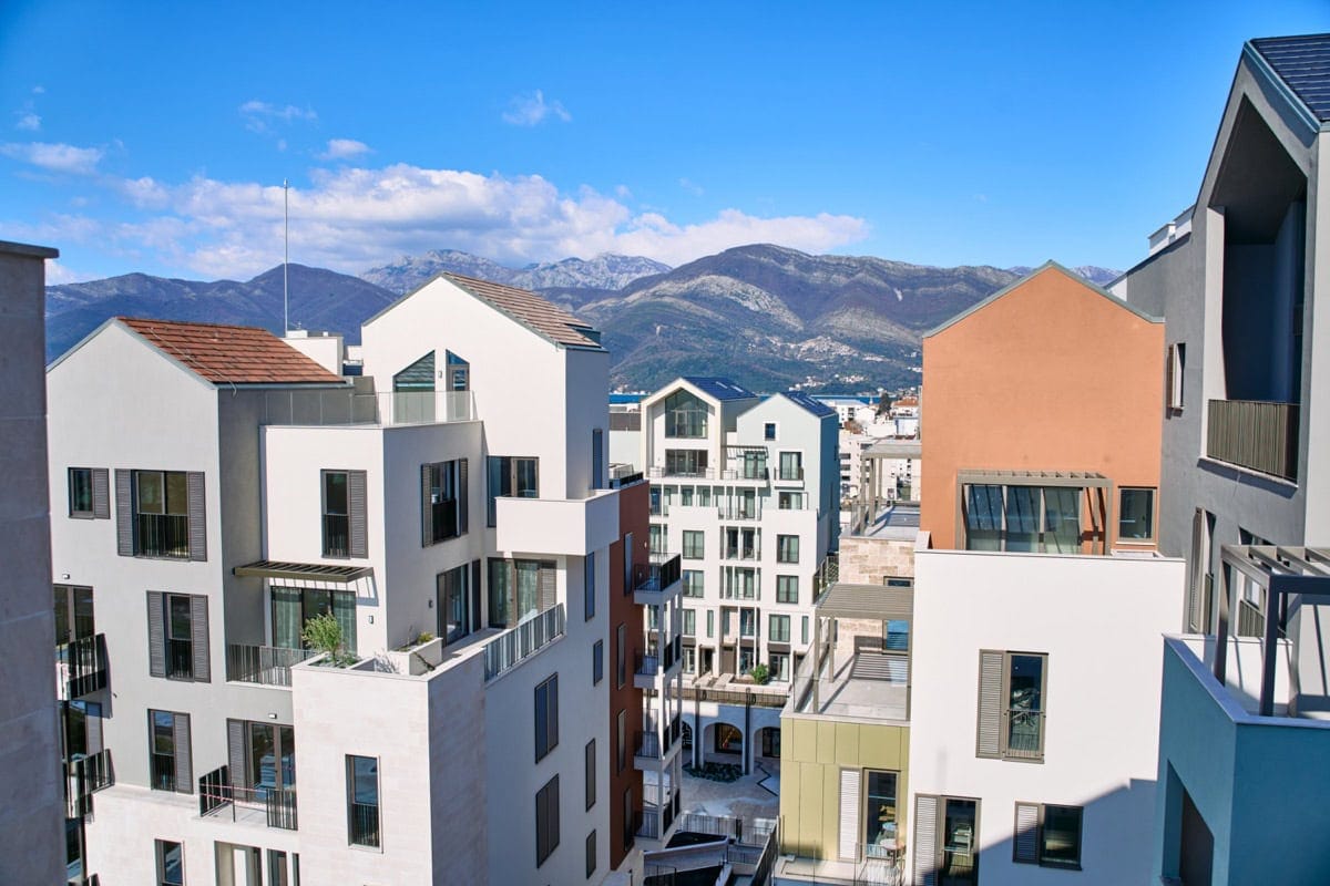 View of modern residential buildings in Tivat, Montenegro, with a panoramic view of the mountains and city architecture.