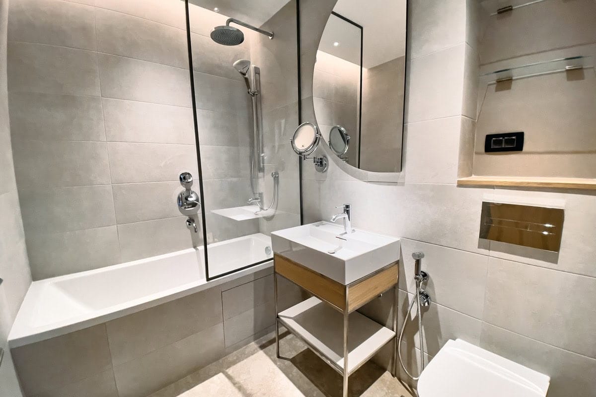 Modern bathroom in an apartment in Tivat, Montenegro: light tiles, bathtub with glass screen, stylish fixtures.