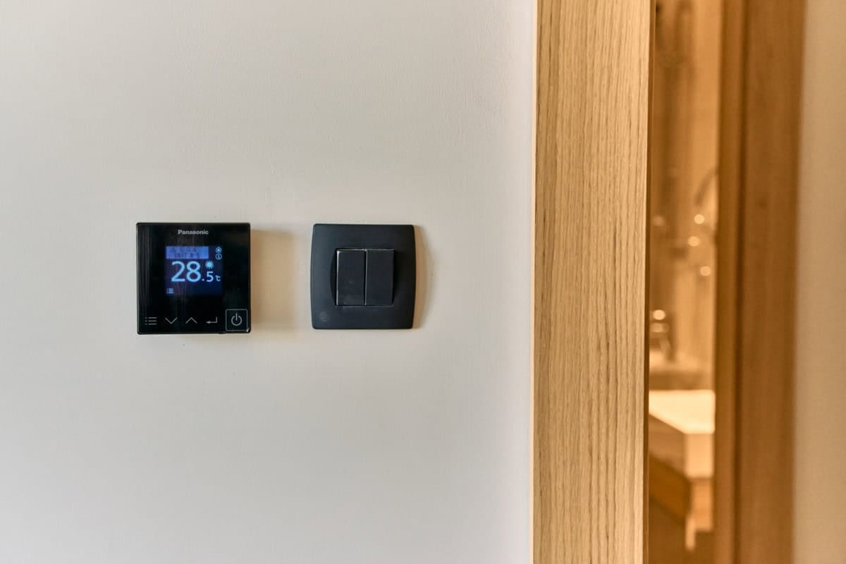 Panasonic thermostat and light switch in a modern apartment in Tivat, Montenegro, with wood finish.