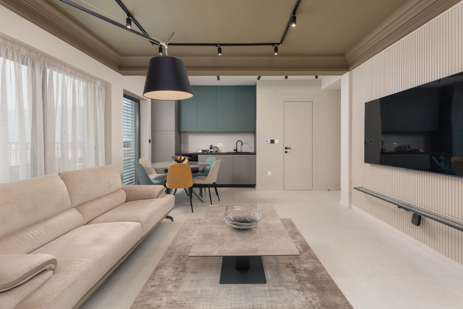 Modern living room with kitchen in an apartment in Dobrota, Montenegro: beige sofa, stylish furniture, and track lighting.