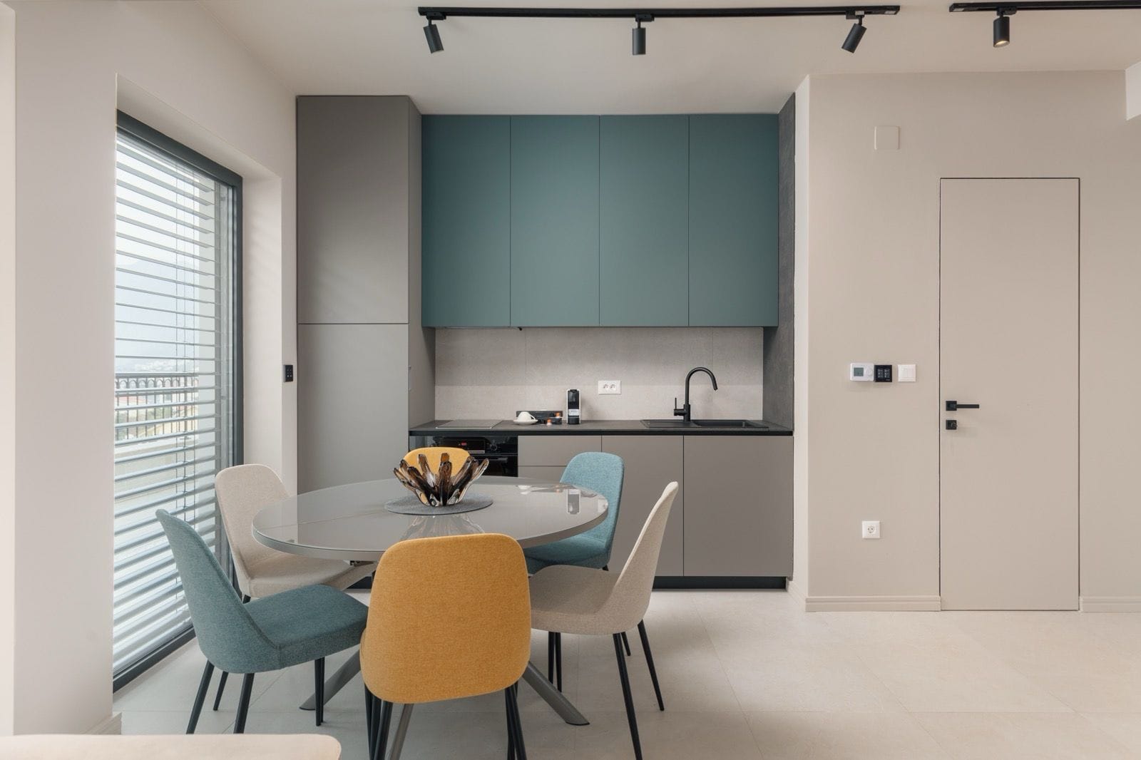 Modern kitchen in an apartment in Dobrota, Montenegro: stylish cabinetry, a round dining table, and bright chairs.