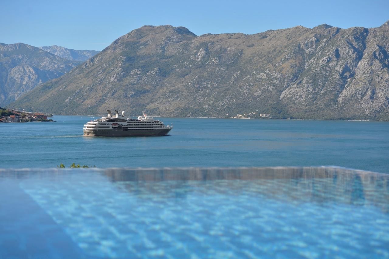 View of the Bay of Kotor and a cruise ship from the infinity pool of an apartment in Dobrota, Montenegro.