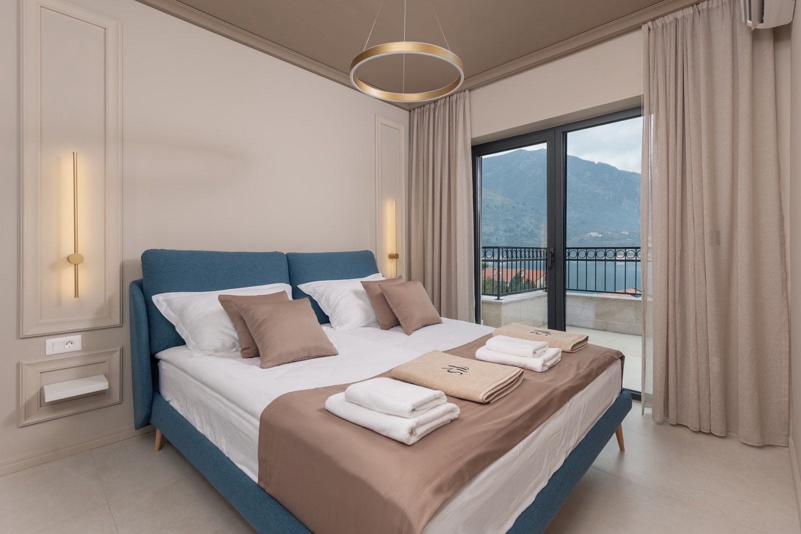 Modern bedroom in an apartment in Dobrota, Montenegro: double bed, panoramic sea and mountain views from the balcony.