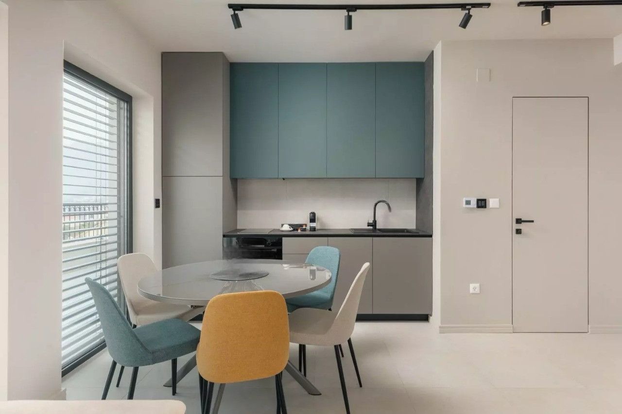Modern kitchen in an apartment in Dobrota, Montenegro: stylish cabinetry, a round dining table, and bright chairs.