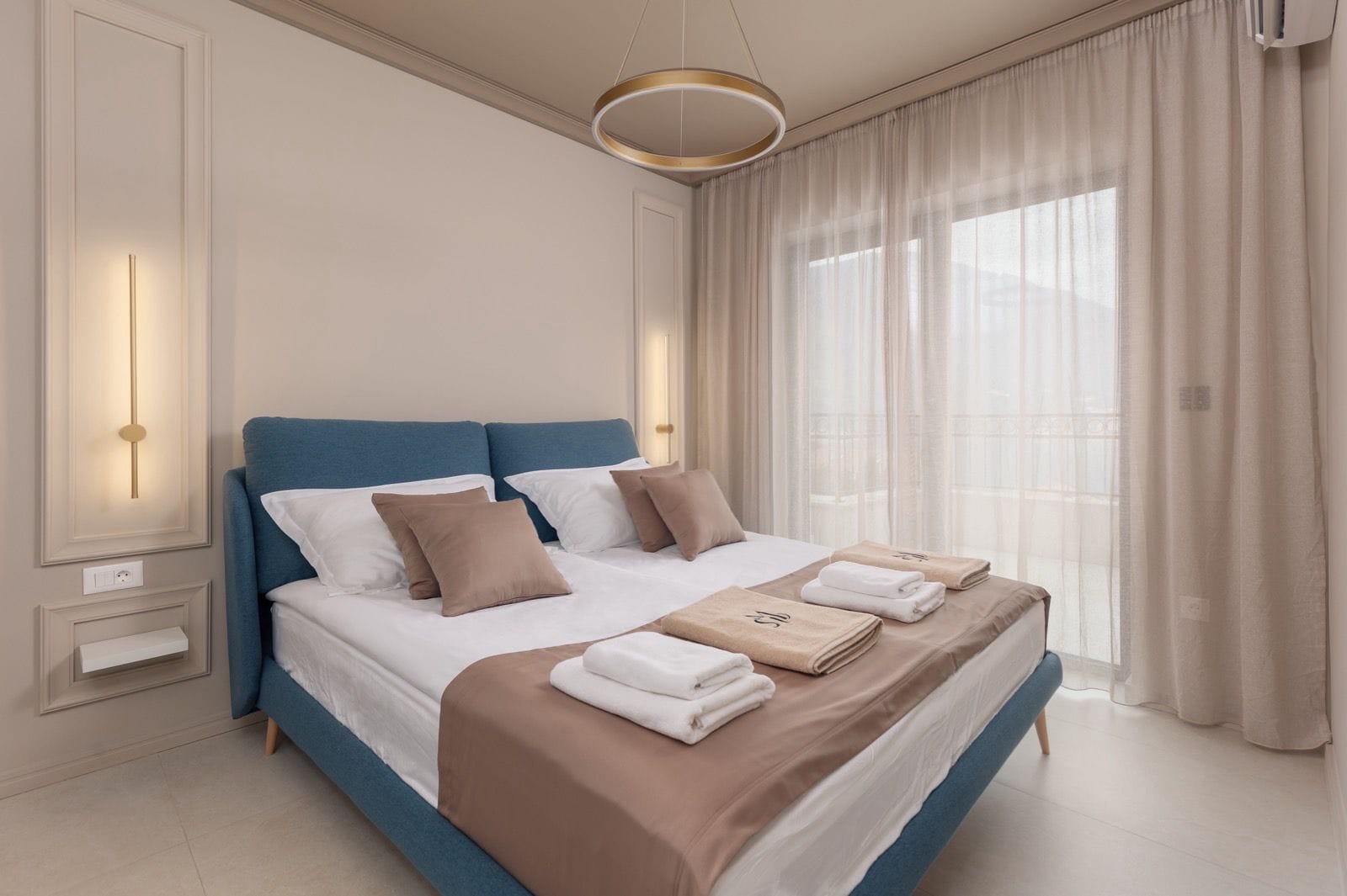 Modern bedroom with a blue bed in an apartment in Dobrota, Montenegro: stylish interior, panoramic window, and balcony.
