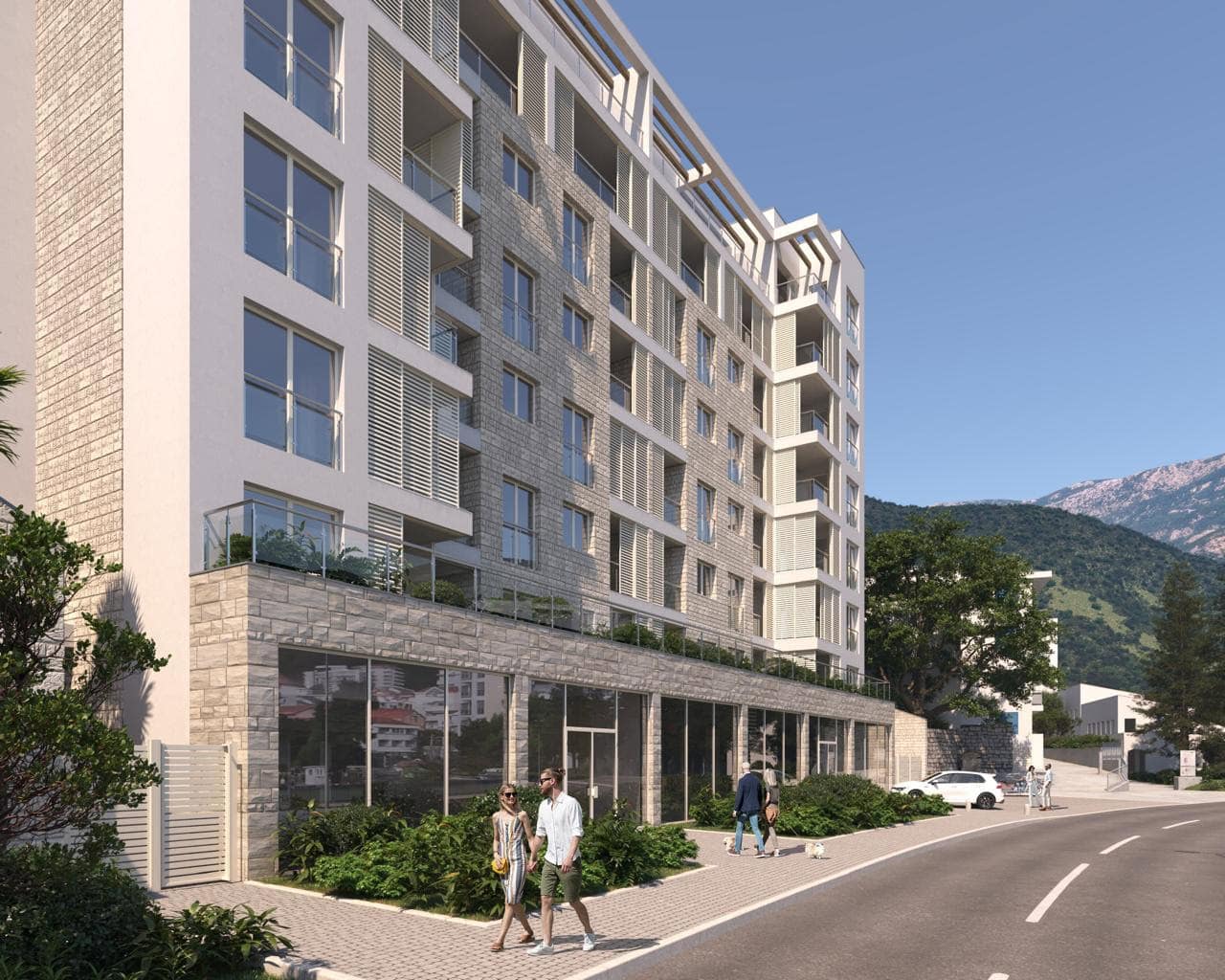 Modern residential complex in Bečići, Montenegro: building facade with panoramic windows, balconies, and mountain scenery.