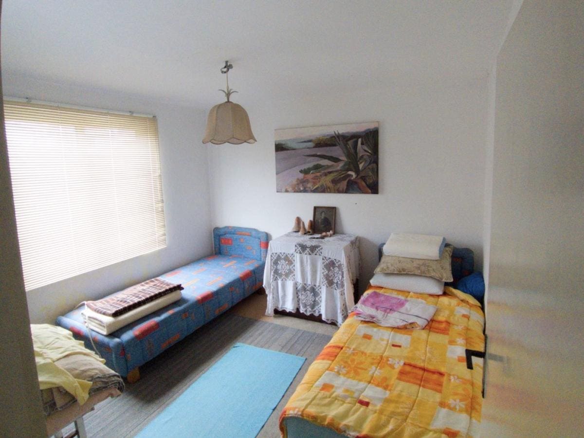 Bright bedroom with two beds in a house for sale, Dobri Vody, Montenegro. Interior with a painting and blinds on the window.