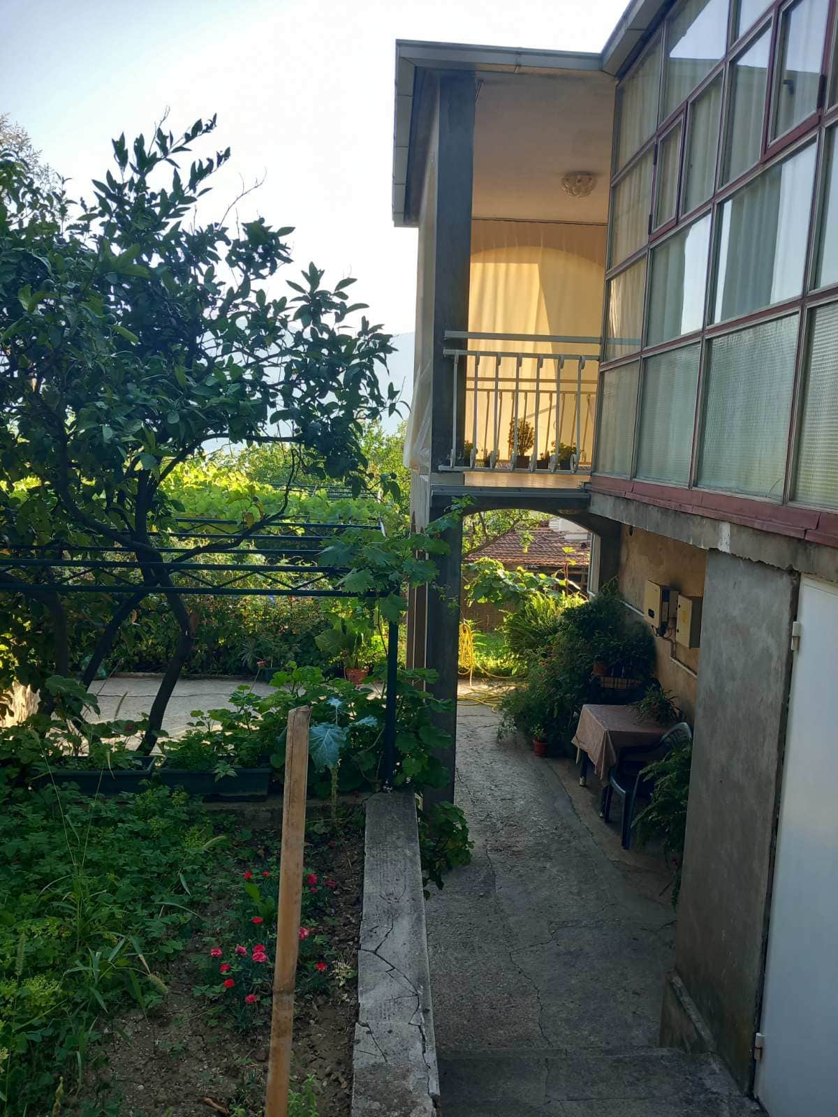 Two-story house in Igalo, Montenegro: terrace, panoramic windows, and a green garden with a vineyard in the yard.