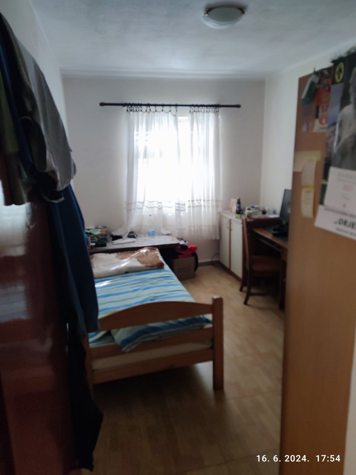 Bedroom in a house in Igalo, Montenegro: a single bed, a desk, light walls, and a window with sheer curtains.