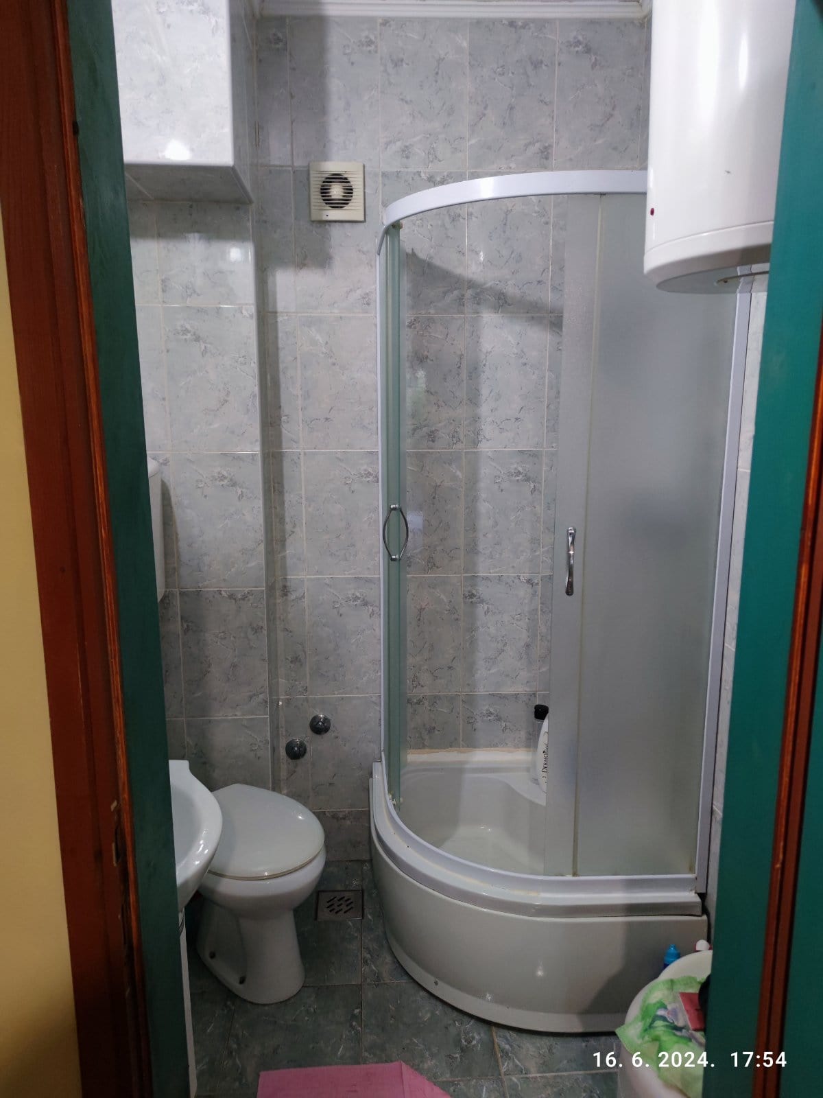 Bathroom in a house in Igalo, Montenegro: shower cabin, plumbing fixtures, and light-colored tiles on the walls and floor.