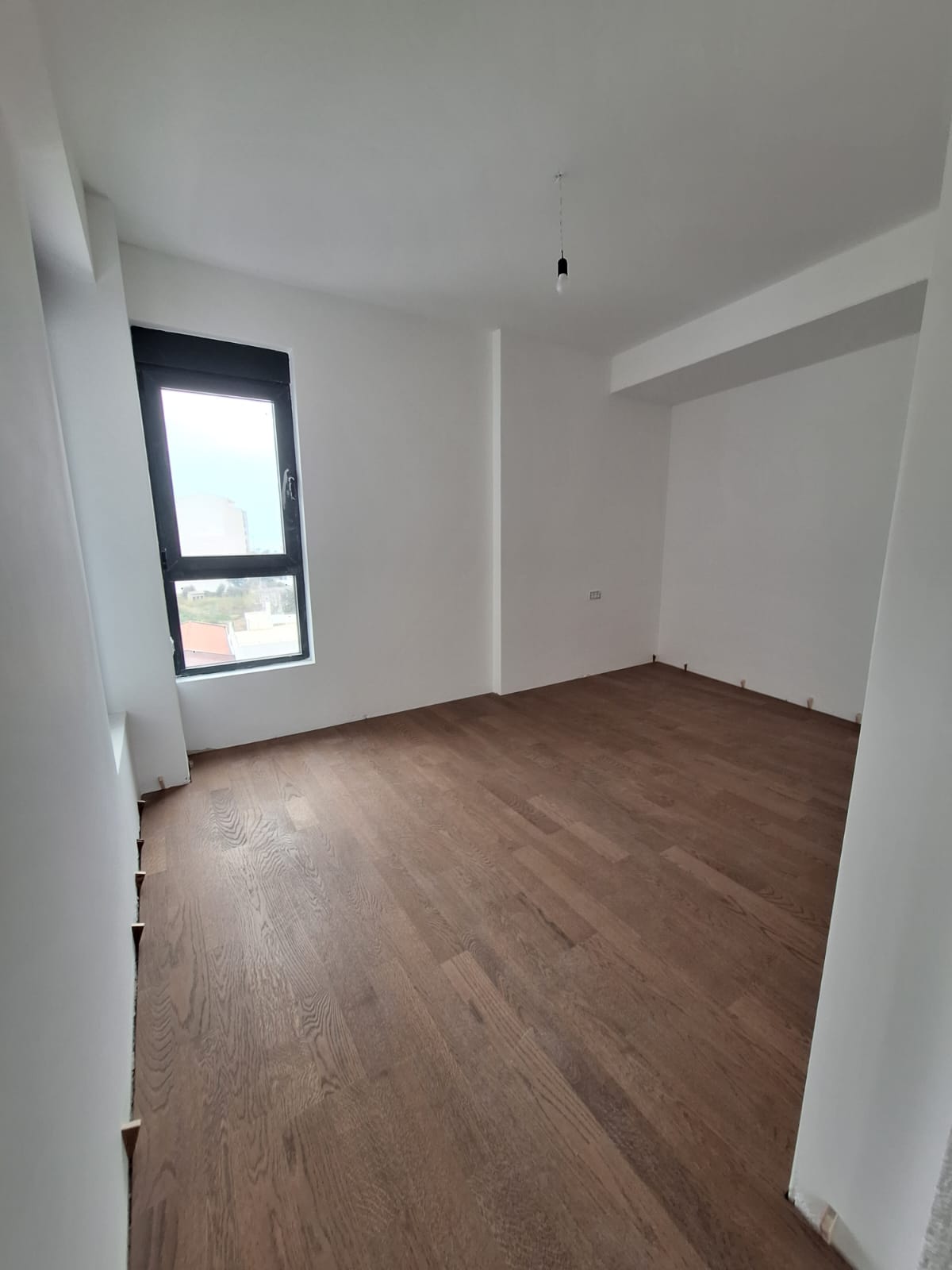 Bright bedroom with parquet flooring in a new apartment, Bar, Montenegro. City view from the window.