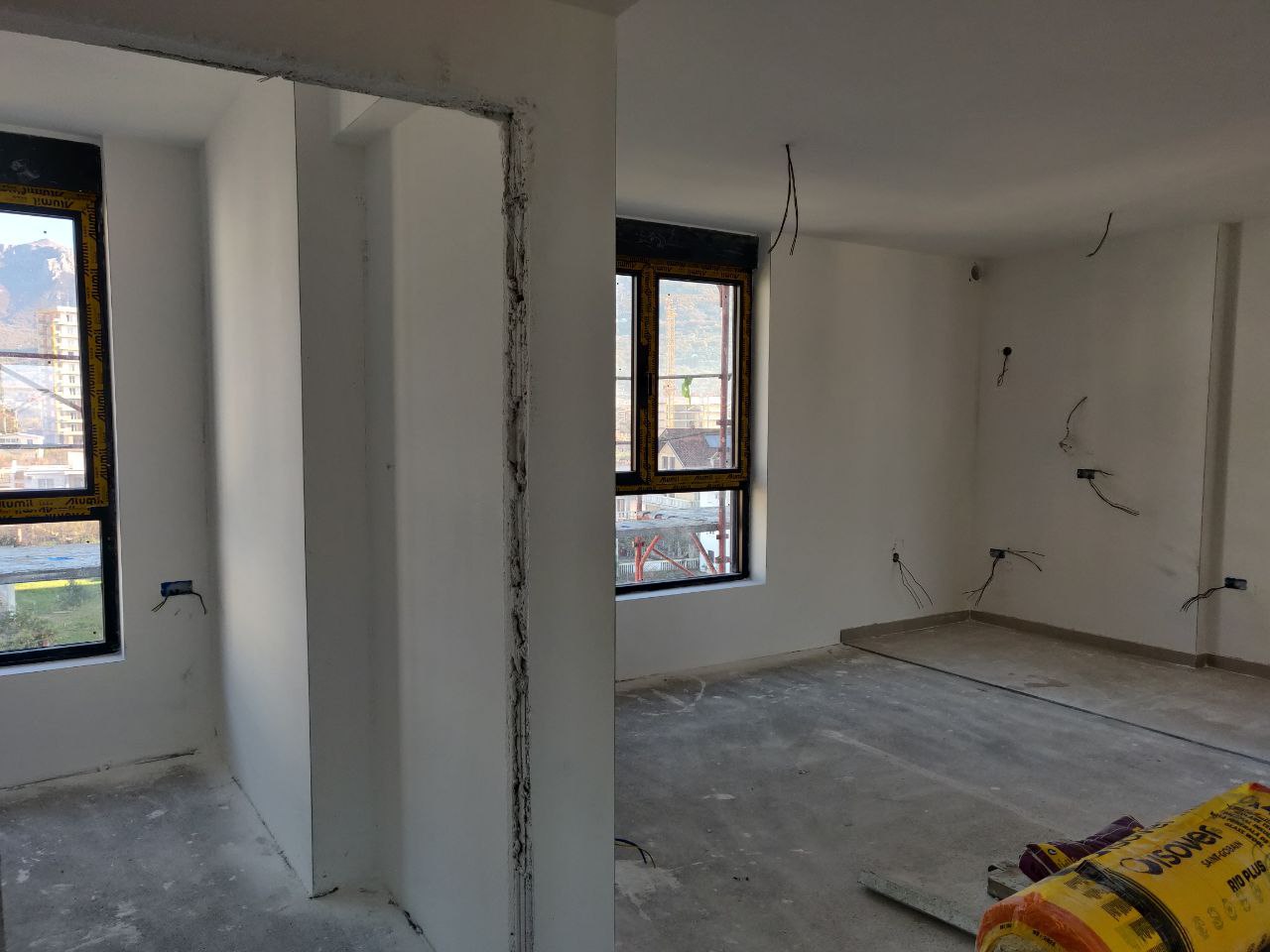 Living room in a new building in Bar, Montenegro: pre-finished interior, panoramic windows, and mountain views.