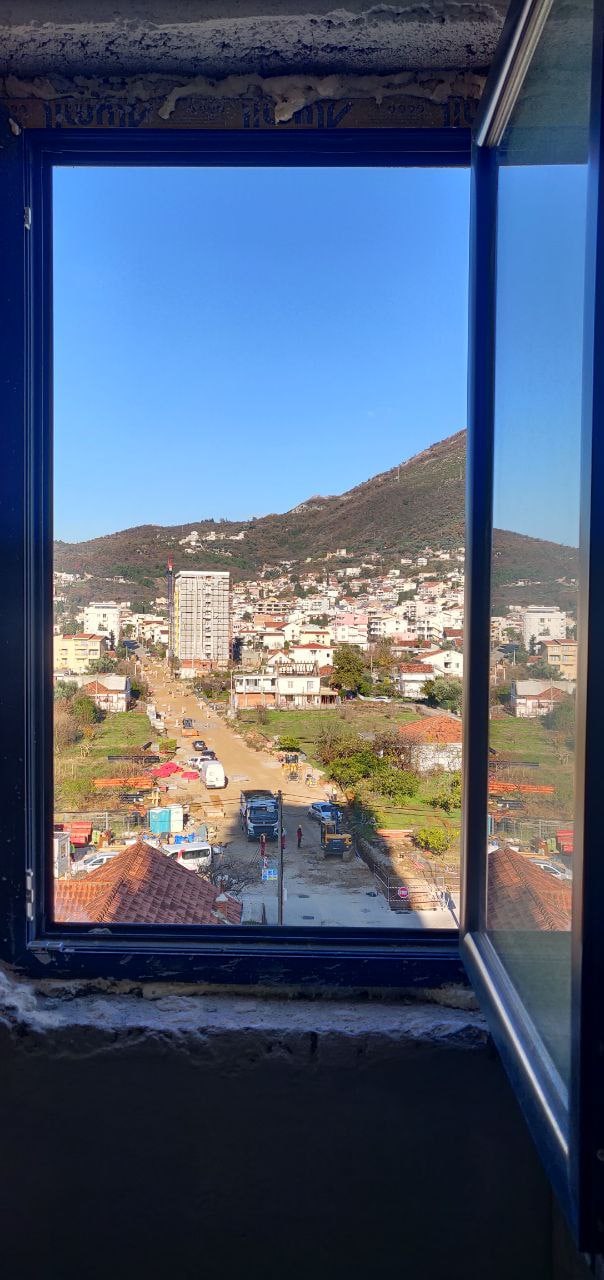 View from the apartment window in Bar, Montenegro: a panorama of mountains, city buildings, and a construction site.