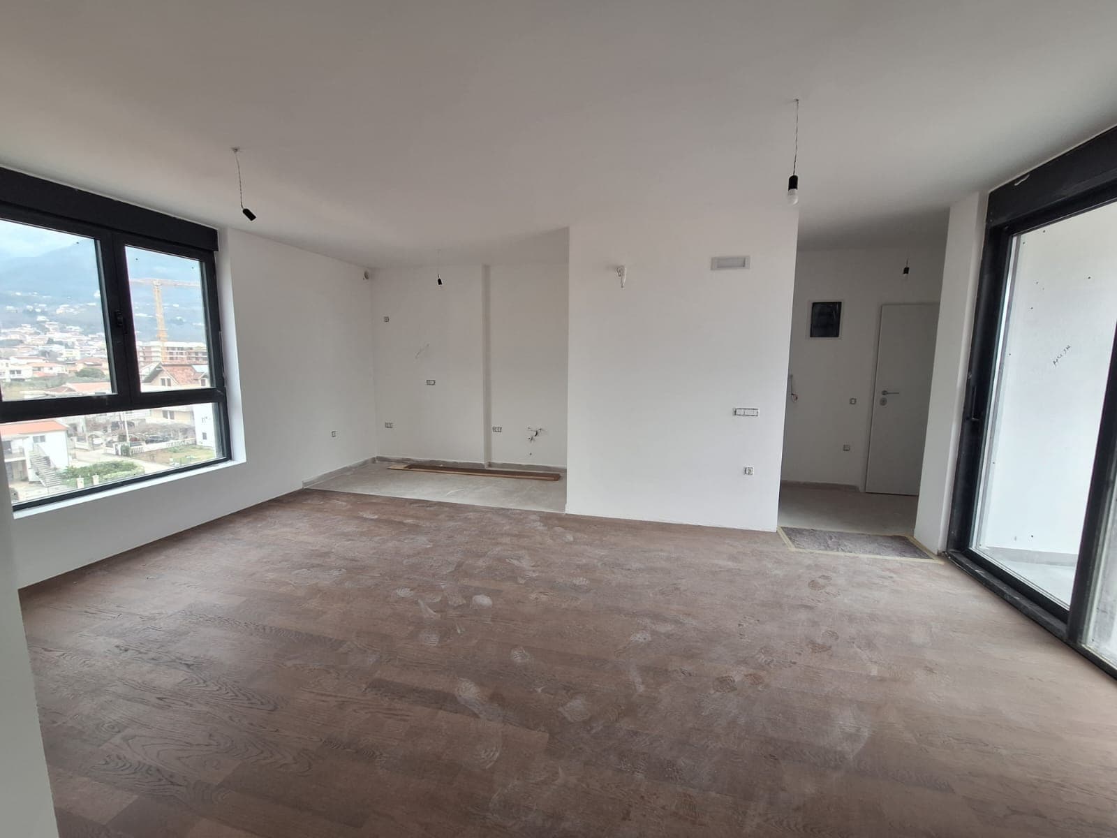 Bright living room with panoramic windows and parquet flooring in a new unfinished apartment in Bar, Montenegro.