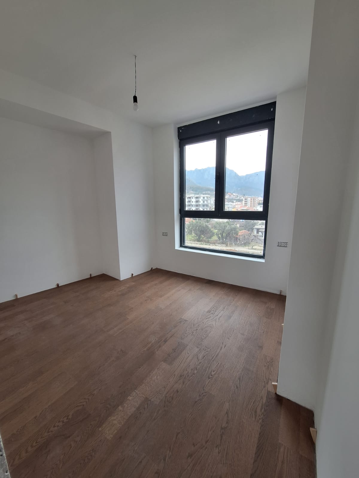 Bright bedroom with parquet flooring and mountain views in a new apartment in Bar, Montenegro.