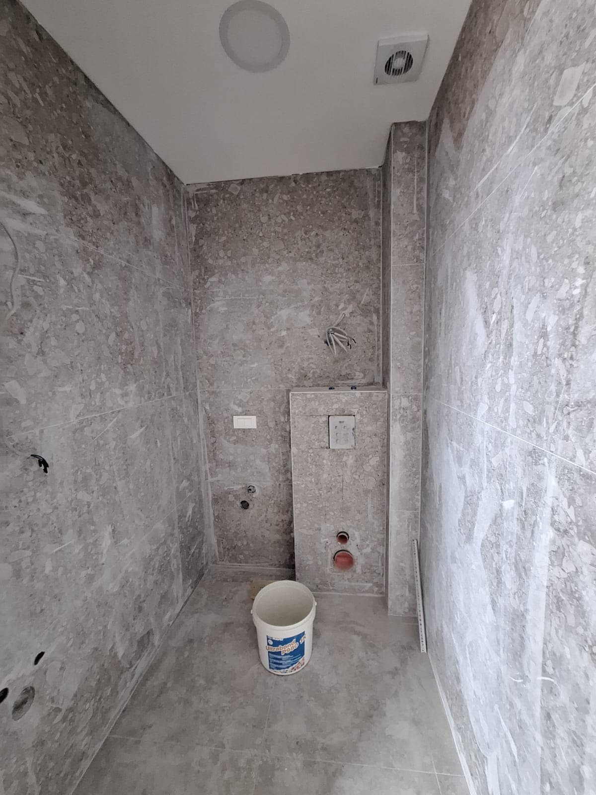 Bathroom renovation in an apartment, Bar, Montenegro: walls finished with gray stone-look tiles, wall-hung toilet installation.