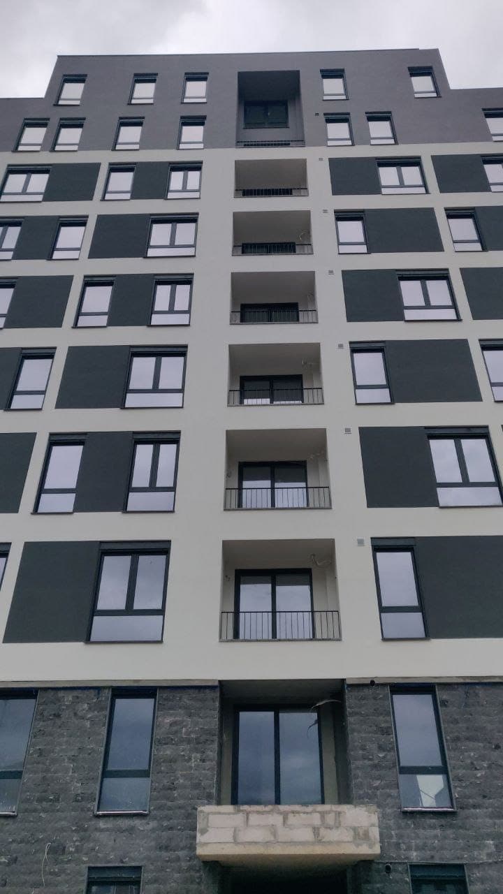 Modern apartment building in Bar, Montenegro: facade with balconies and panoramic windows, viewed from below.