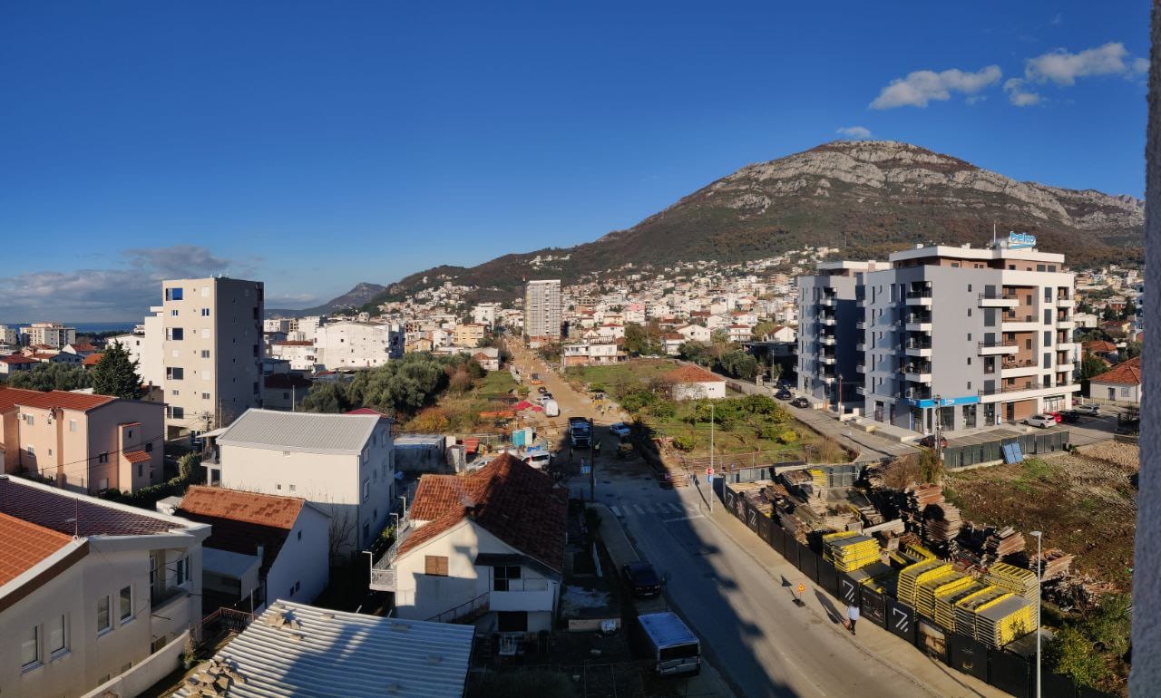 Panoramic view of Bar, Montenegro: residential buildings, mountain scenery, and city infrastructure from the apartment balcony.