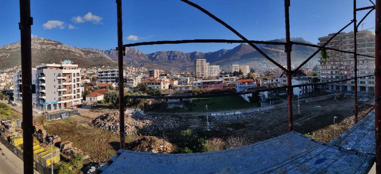 View from the balcony of a house under construction in Bar, Montenegro: city panorama, mountain scenery, and scaffolding.